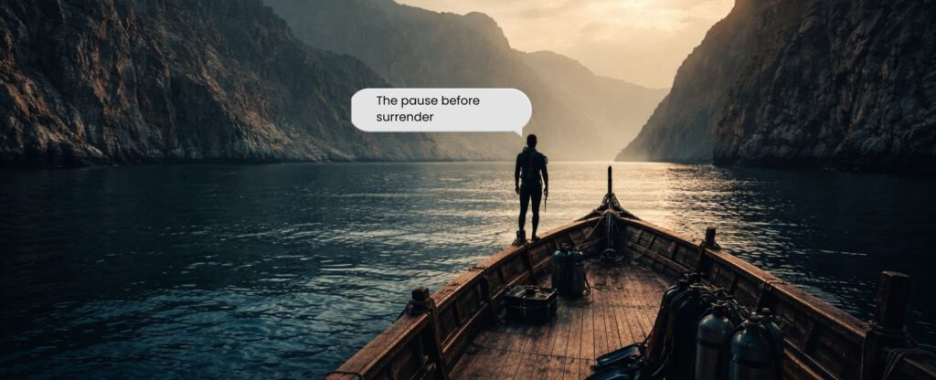 Best scuba diving trip from Dubai as a diver stands on a traditional dhow in Musandam, surrounded by dramatic fjord-like cliffs and calm open water.